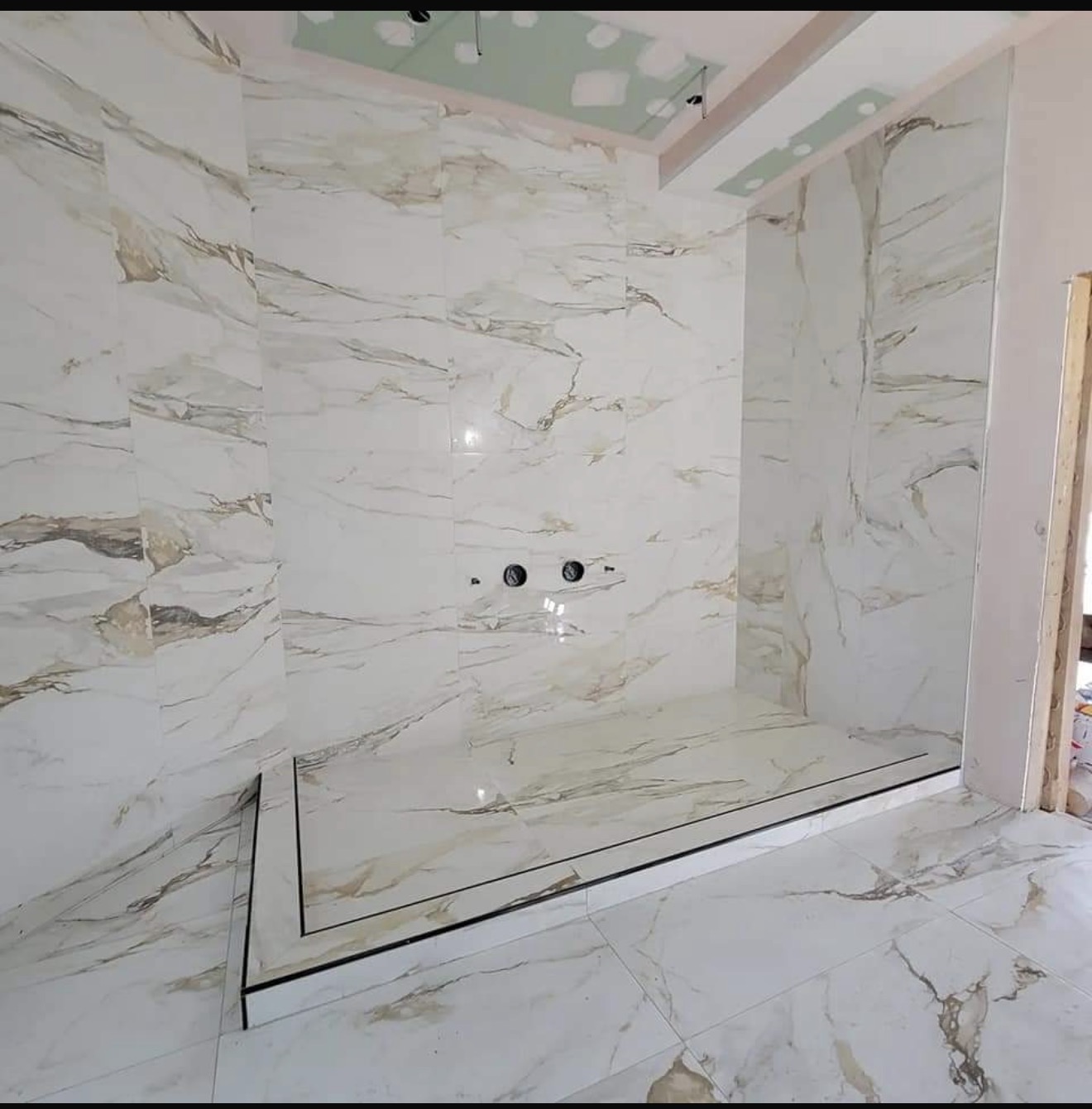 Calacatta marble shower surround and tile floor installed by LevelUp
